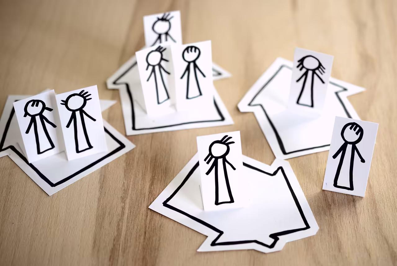 Paper cut-outs of people inside house outlines representing neighbourhood disputes and anti-social behaviour assessment services.