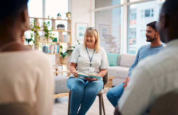 Community mediation session with a female mediator facilitating a small group conversation in a bright, modern room.
